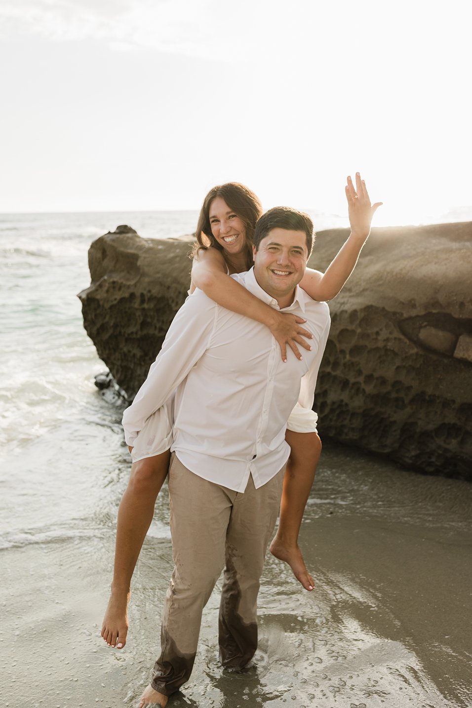 A couple wearing white pose for their engagement photos in La Jolla.