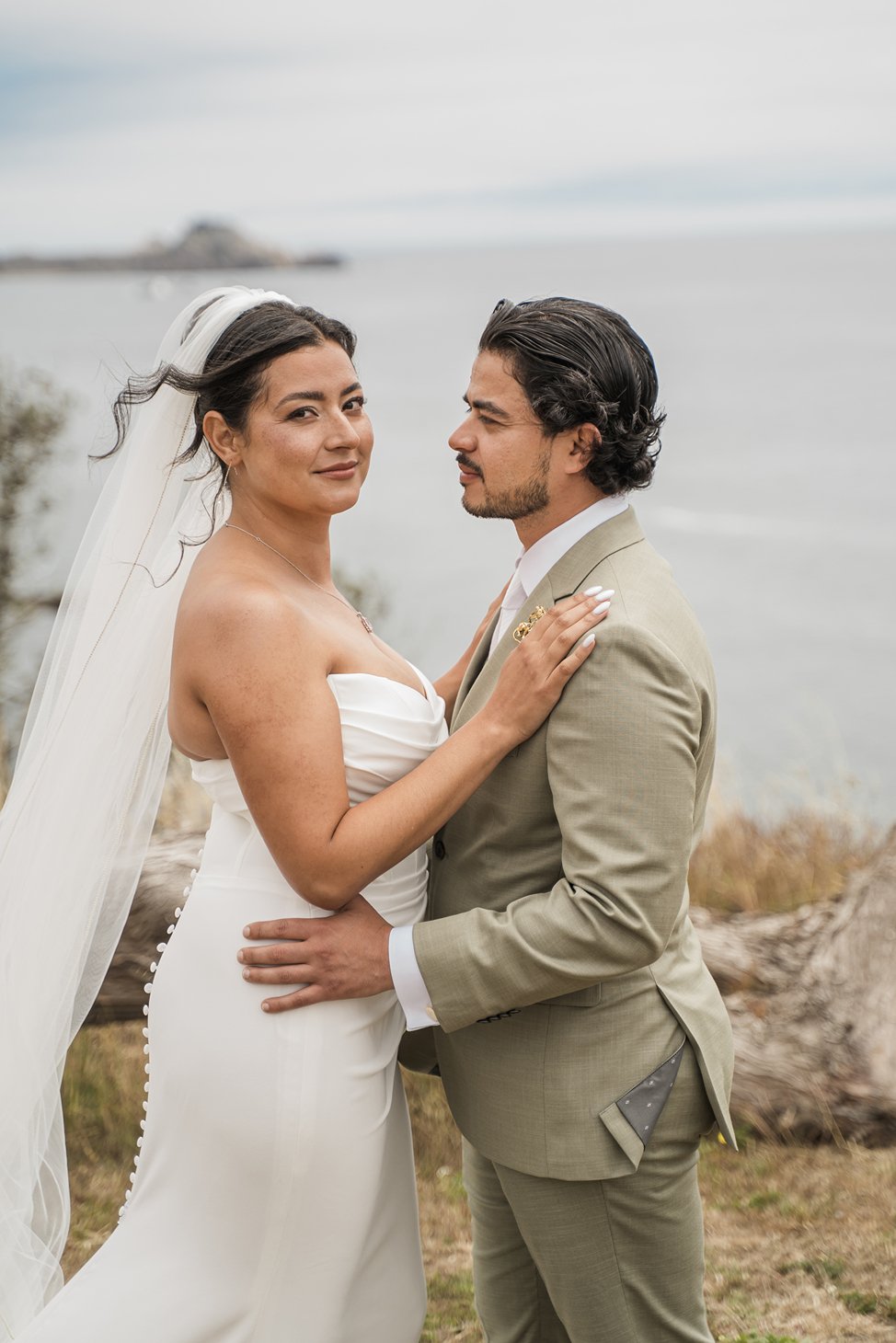 A couple poses together along the water on their wedding day in San Francisco.