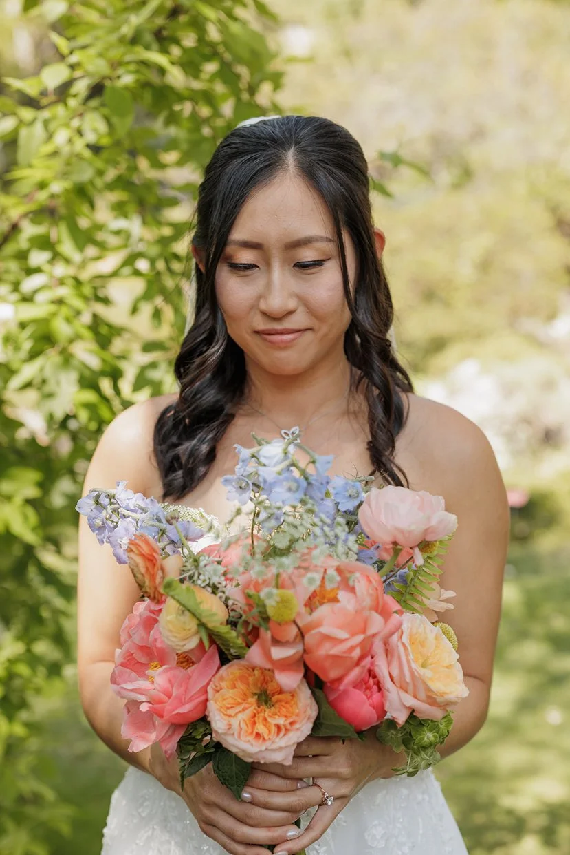 Bride looks down at her colorful Spring bouquet.
