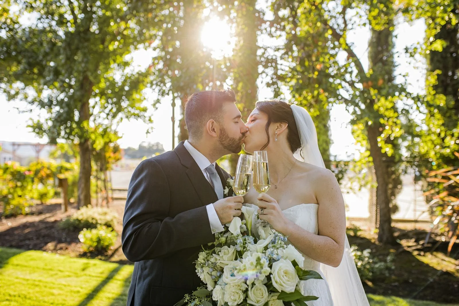 Bride and groom kiss with champagne at Garre Winery wedding ceremony.