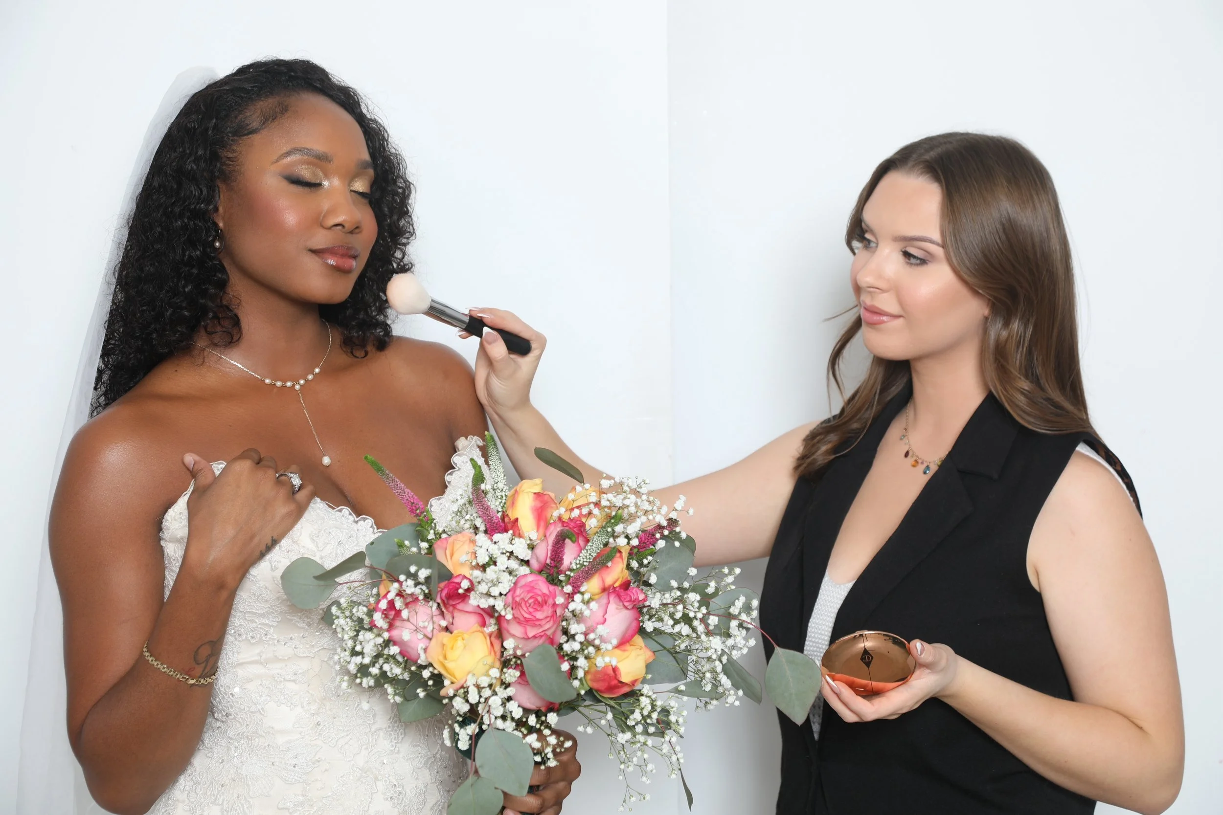 Camille Jones Hair and Makeup touches up makeup on a bride.