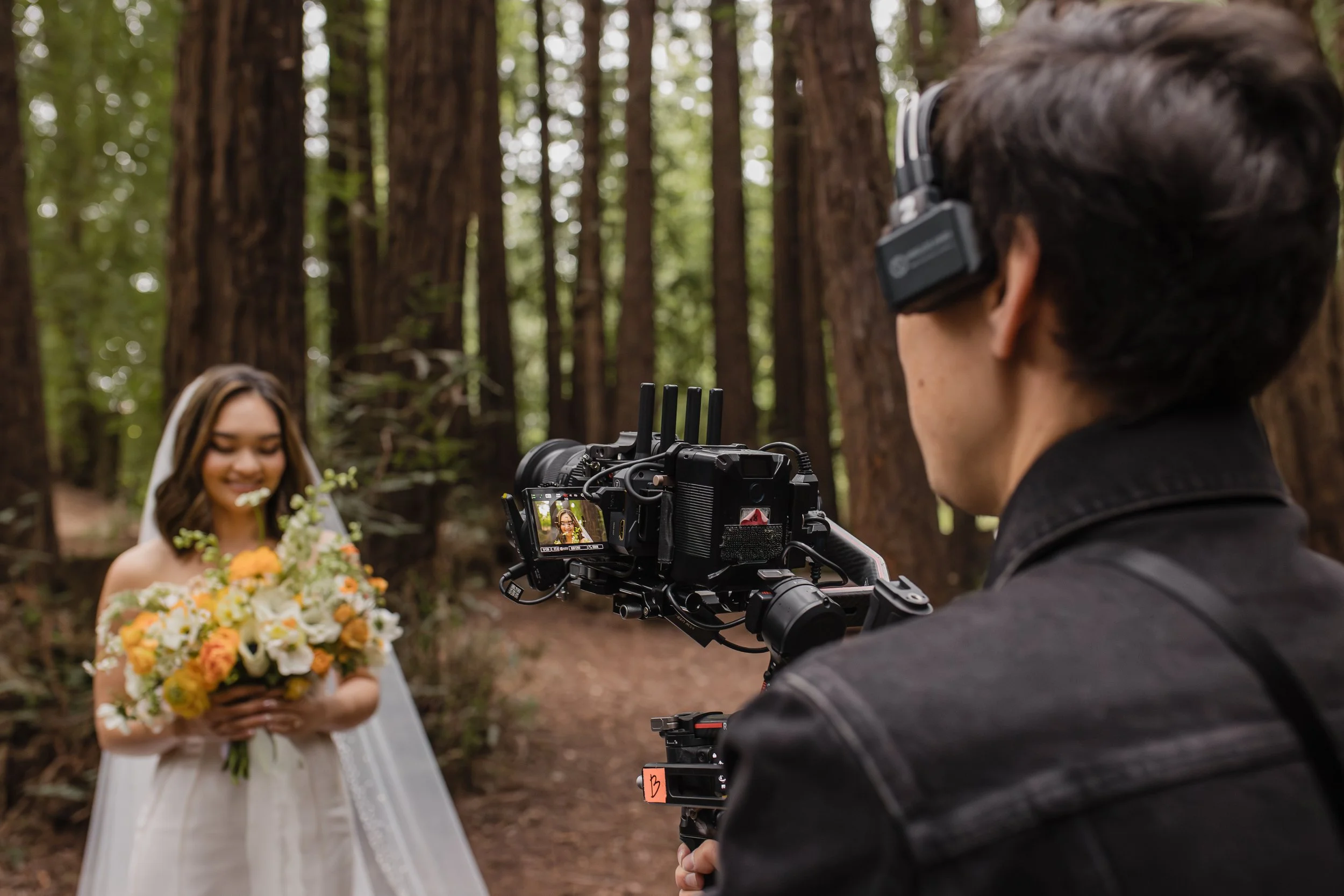 A videographer films a bride and her bouquet in a redwood forest in Mill Valley.