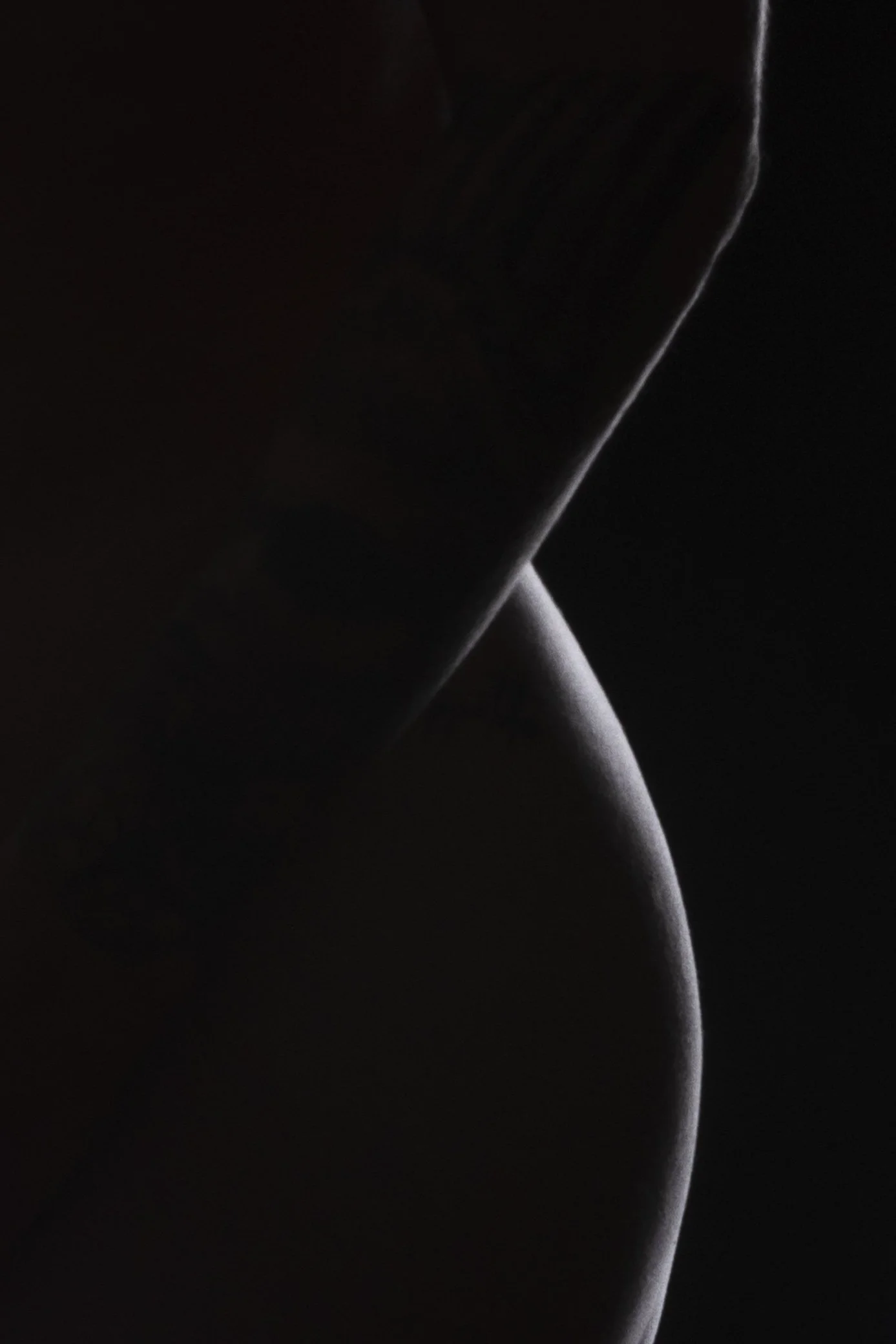 Close-up of a dark, curved surface with subtle lighting highlighting its shape.