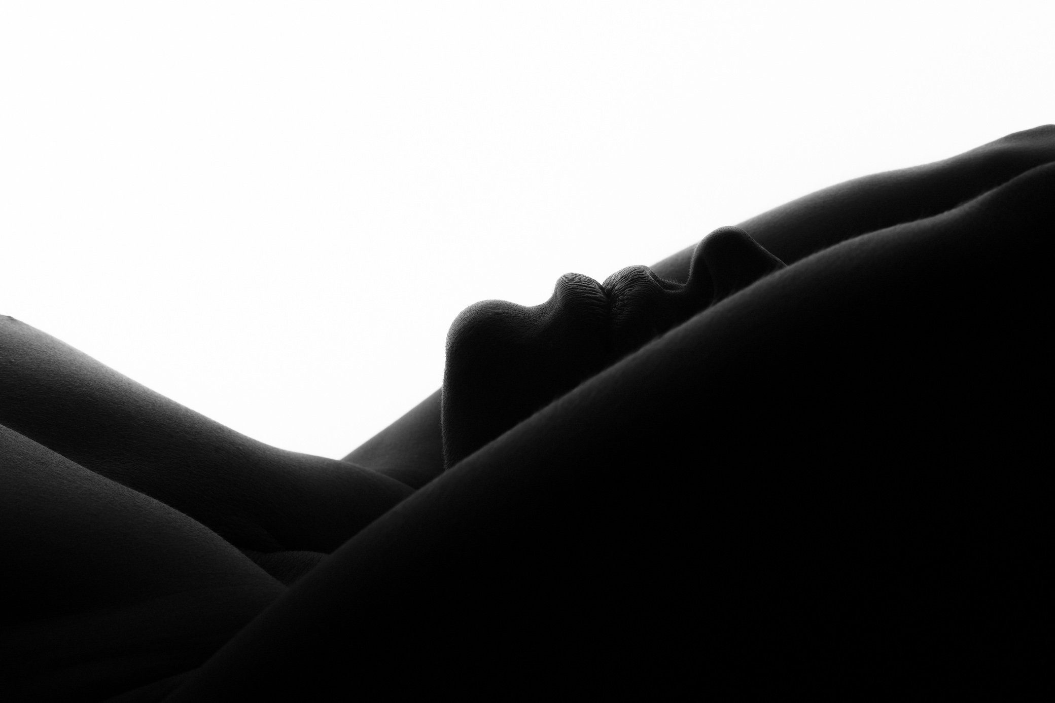 Black and white silhouette of a person lying down with their face in profile against a white background.