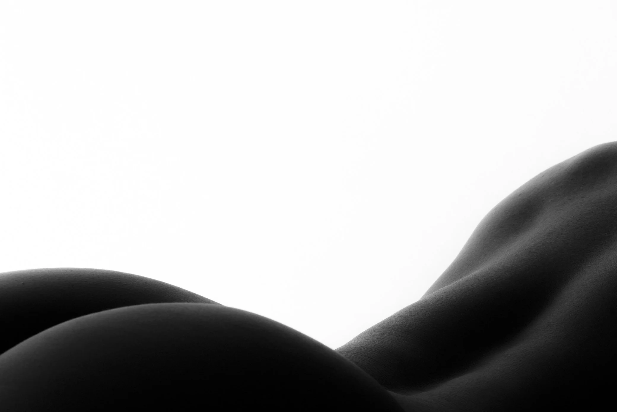 Close-up black-and-white photo of a person's back and shoulder, with smooth skin, against a plain white background.