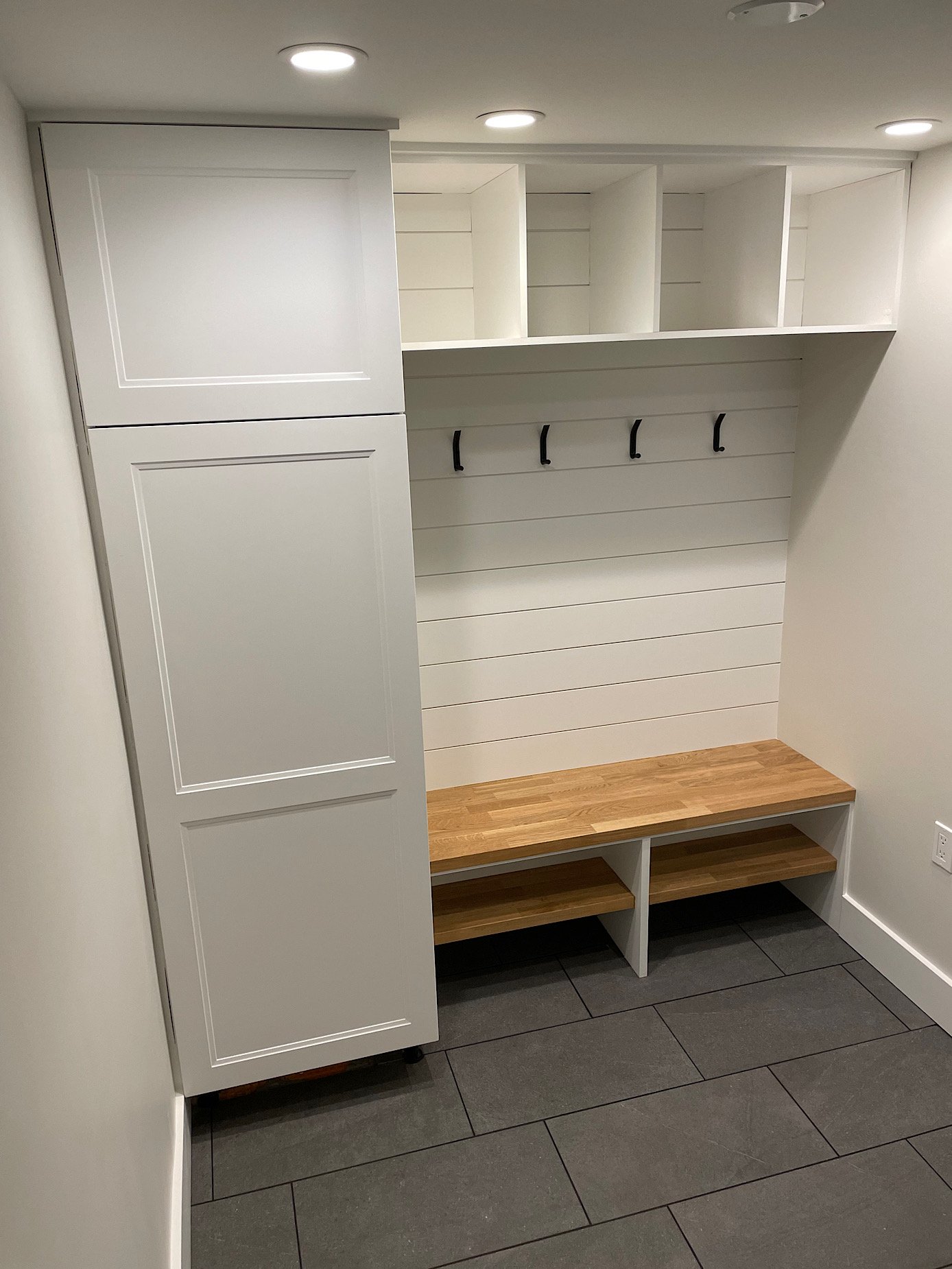 After - shiplap wall installed as a durable option behind bench with coat hooks. Cubbies above and below.