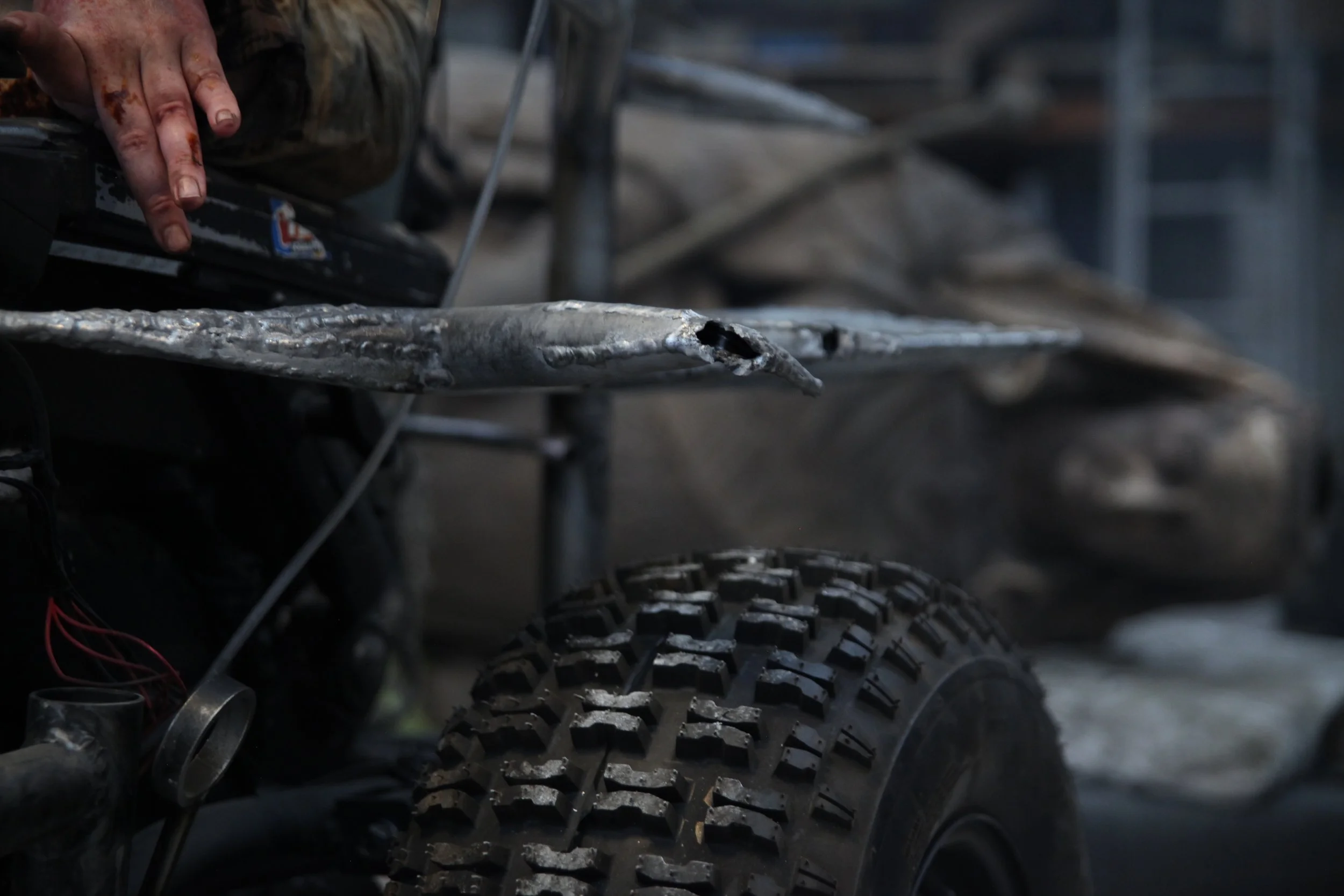The side of my apocalyptic wheelchair shows metal welded together and a monster-sized wheel. My fingers are in a Dystonic pose.