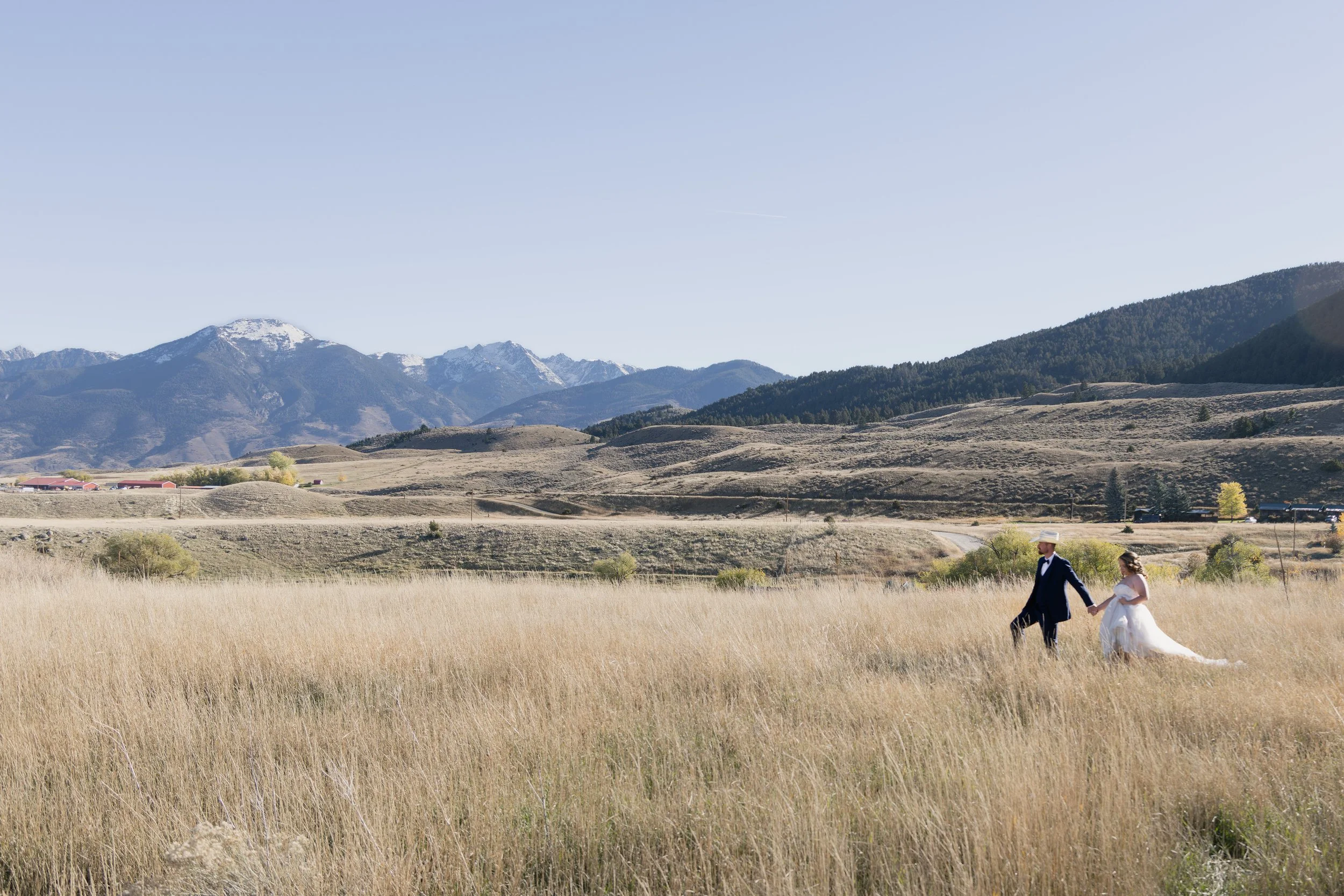 couple walking in a field at Chico Hot Spring near Bozeman Montana captured by Alyssa Johnson Photography Bozeman Wedding Photographer