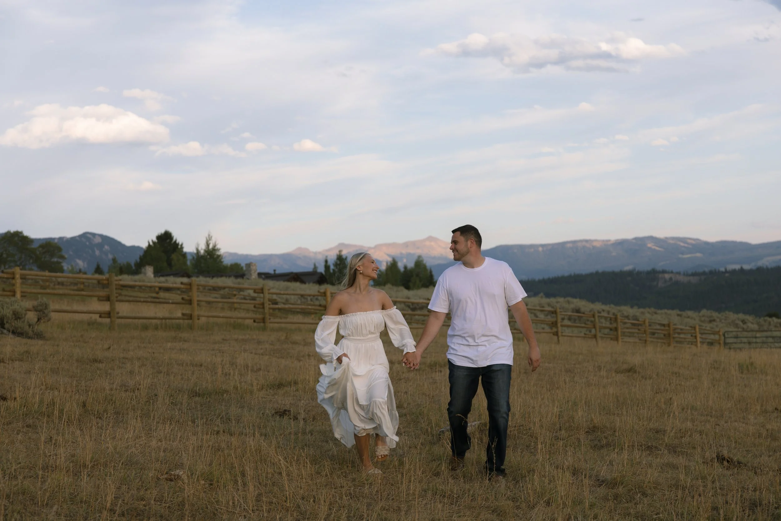 Couple walking together through the Montana landscape during their engagement photos at Lone Mountain Ranch.