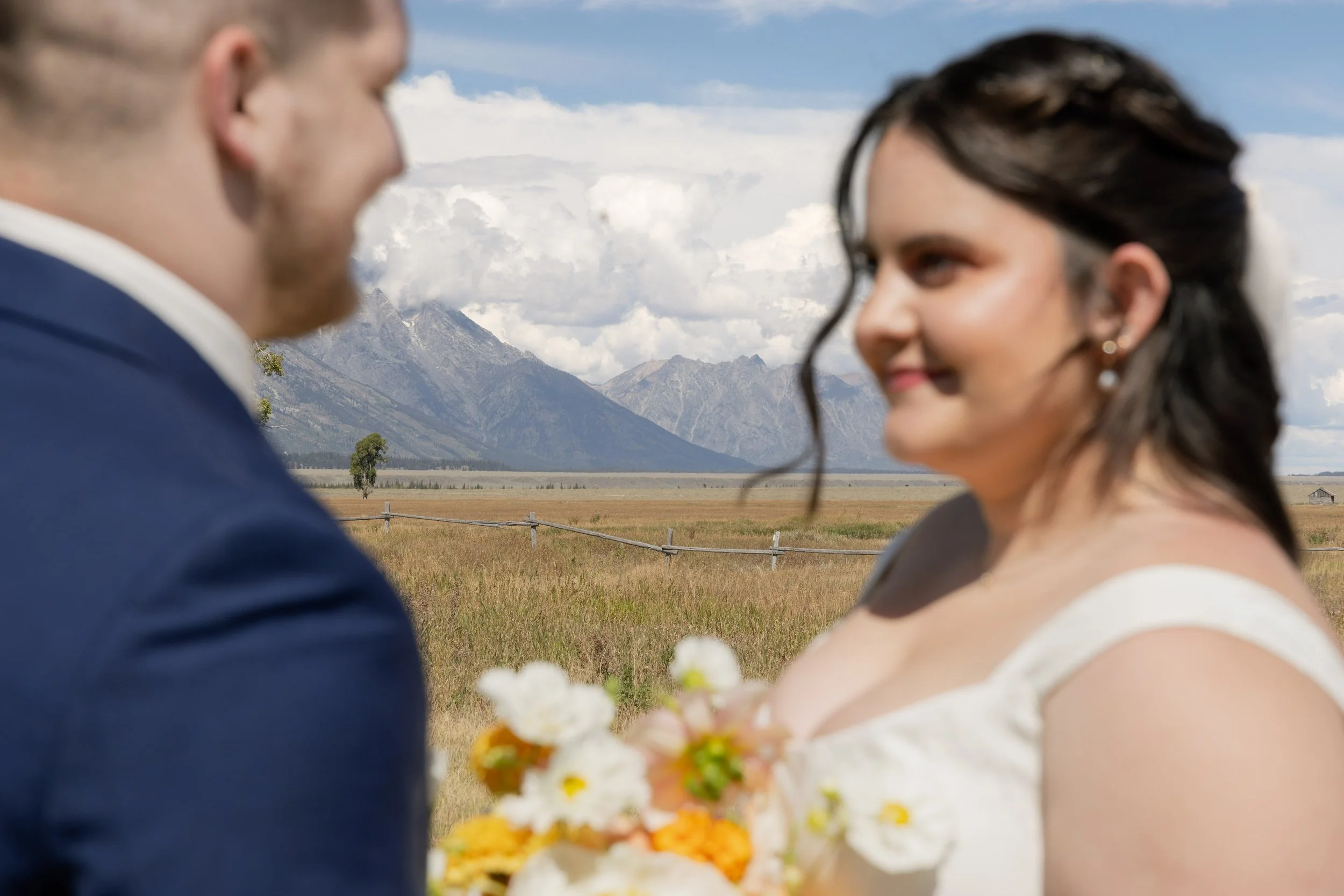 field and mountain of Tetons National Park with bride and groom