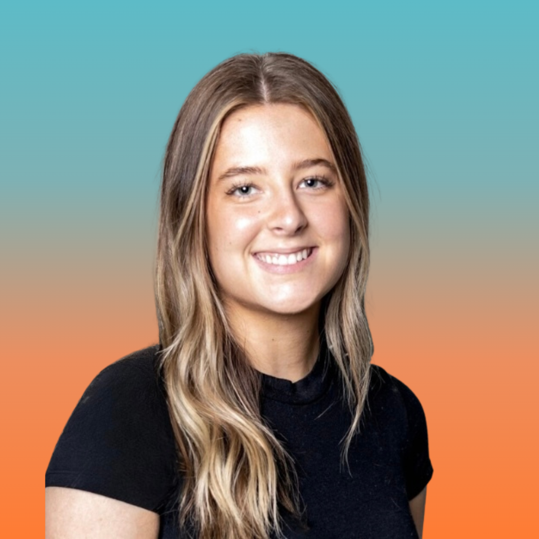 A smiling woman with long blonde hair wearing a short-sleeved back top.