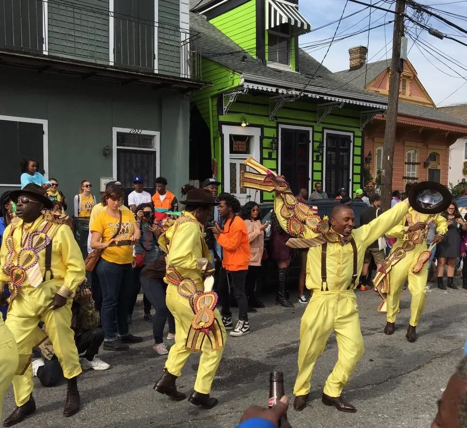 People in yellow costumes dancing and celebrating in a street parade with onlookers watching.
