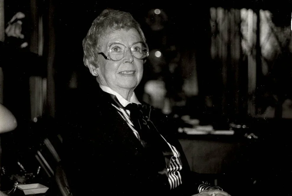 Ida Power looking off to the side, with glasses on and smiling.