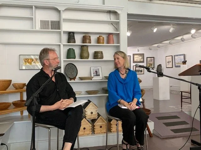 Ron Capps with a black shirt on and author Elisa Speranza with a blue shirt on sitting down with microphones titled towards them.