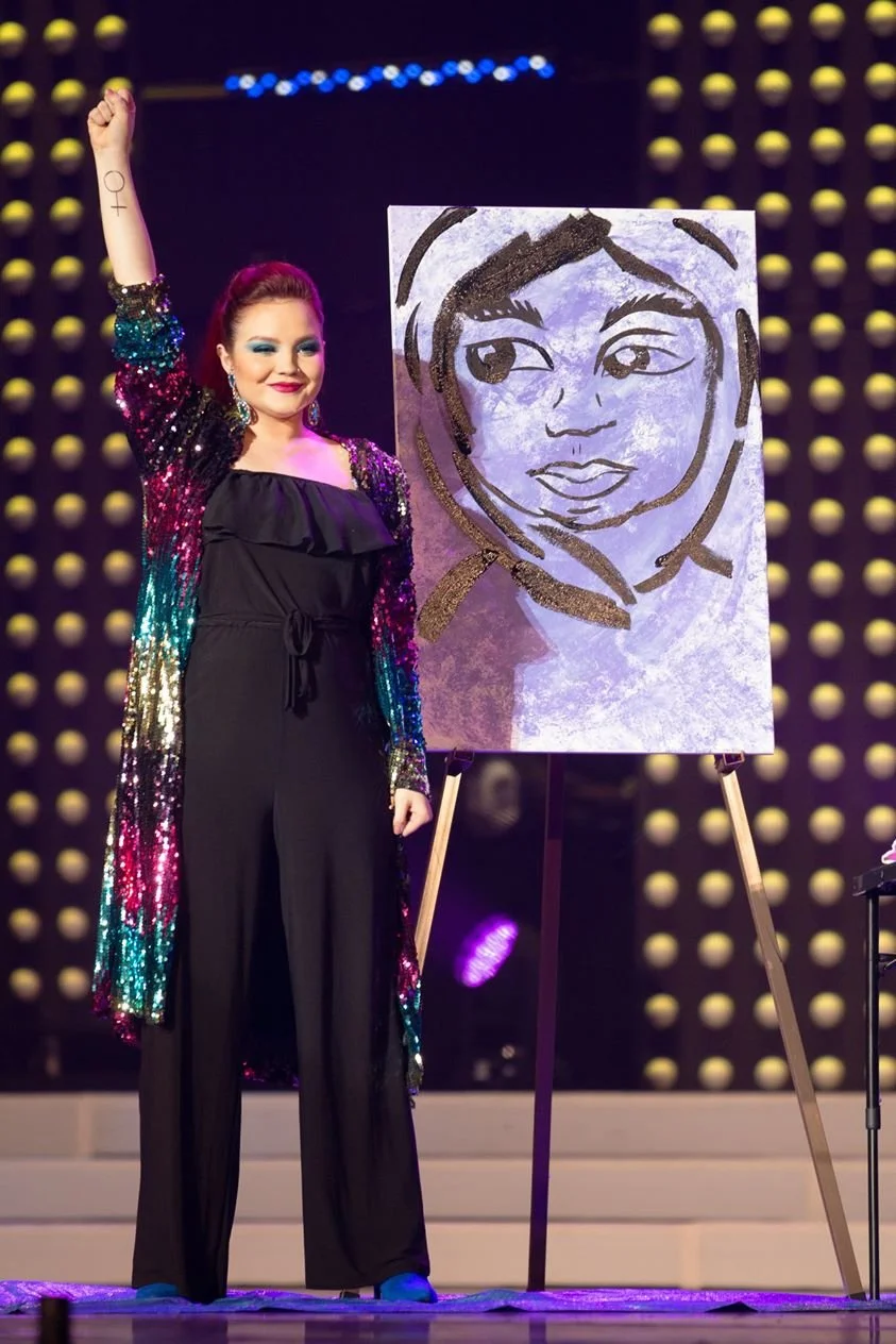 A Miss South Carolina 2019 contestant stands beside her speed painting of Malala Yousafzai.