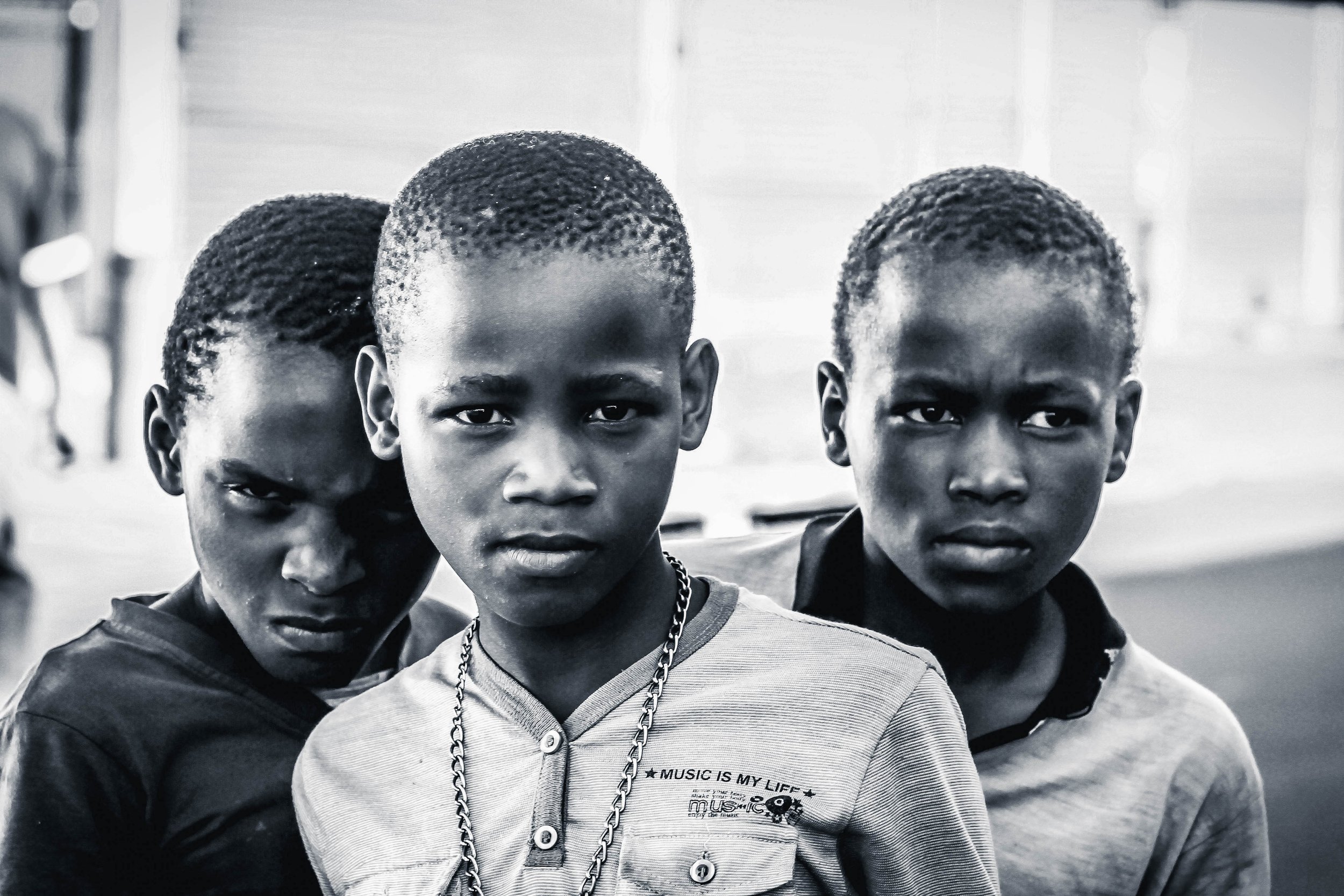 Three young children with intense expressions standing close together, with a blurred background.