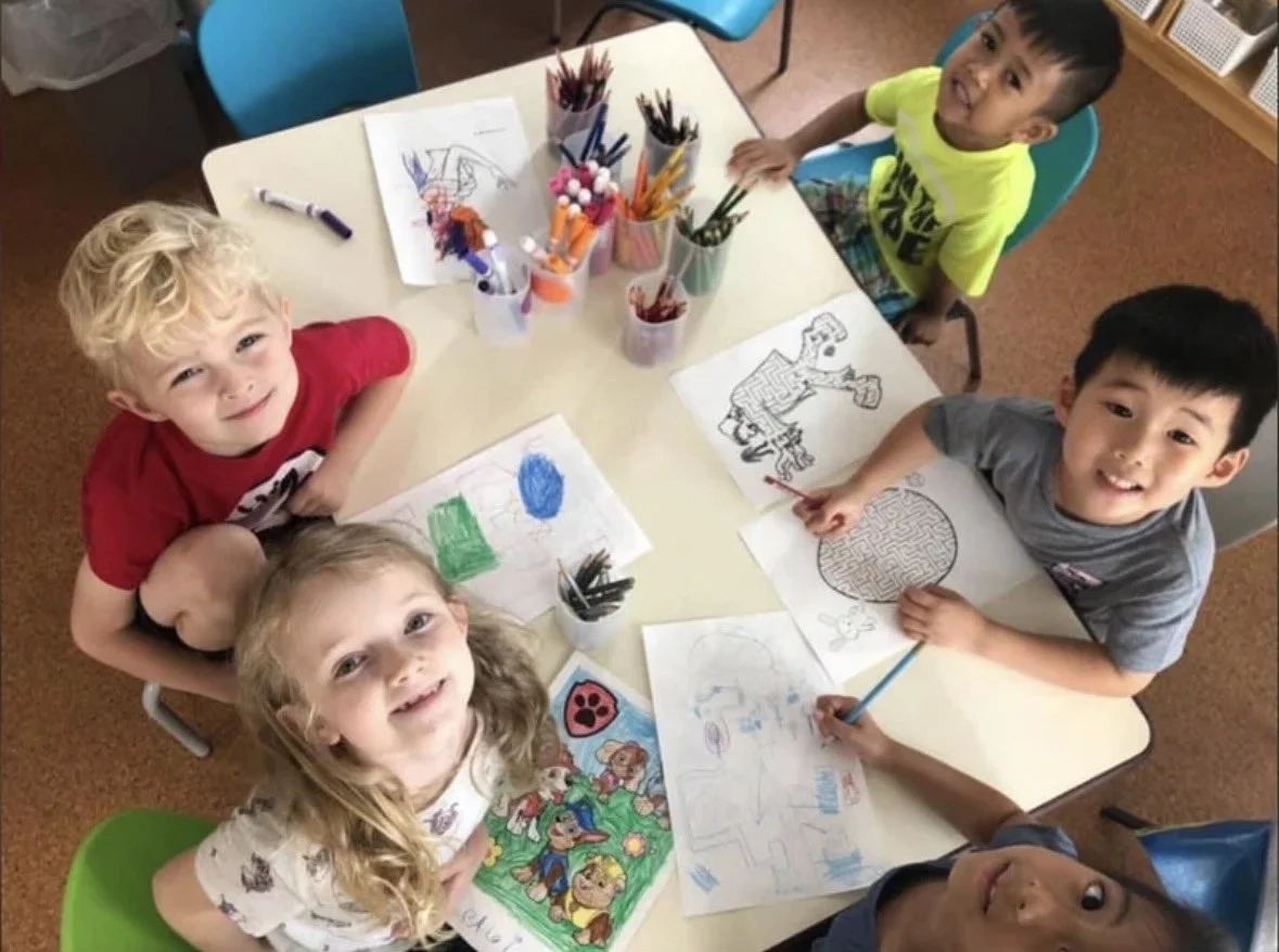 American children holding colorful artwork looking up