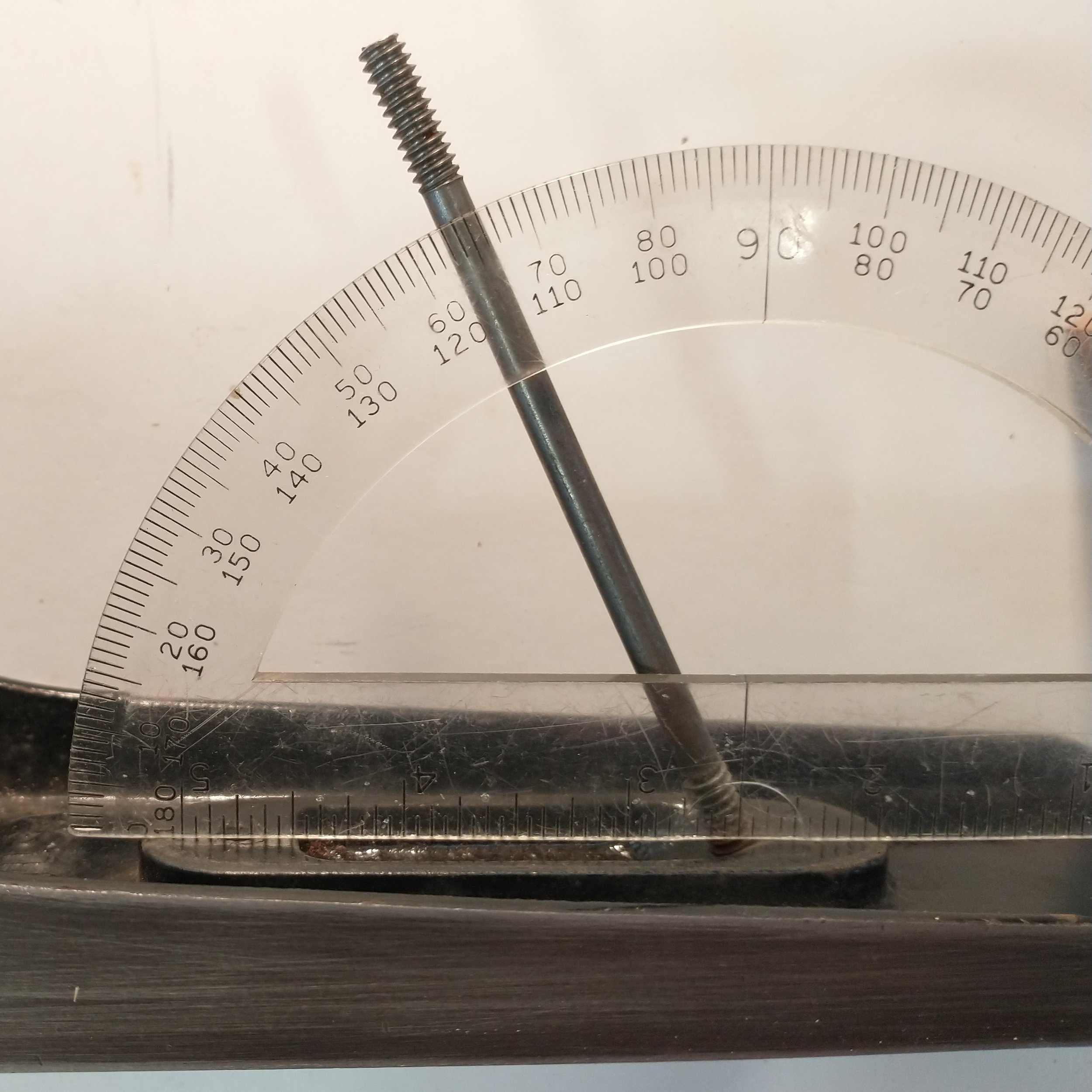 Rest the protractor on the top of the raised tote receiver. Align the vertex point in the center of the double threaded rod. Read the degrees in the middle of the rod.