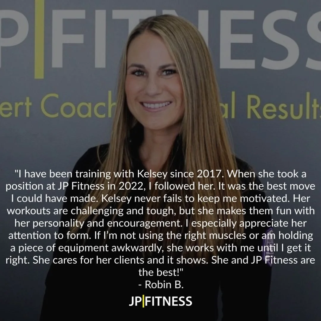 A woman with long blonde hair smiling in front of a JP Fitness backdrop. She is wearing a black top.