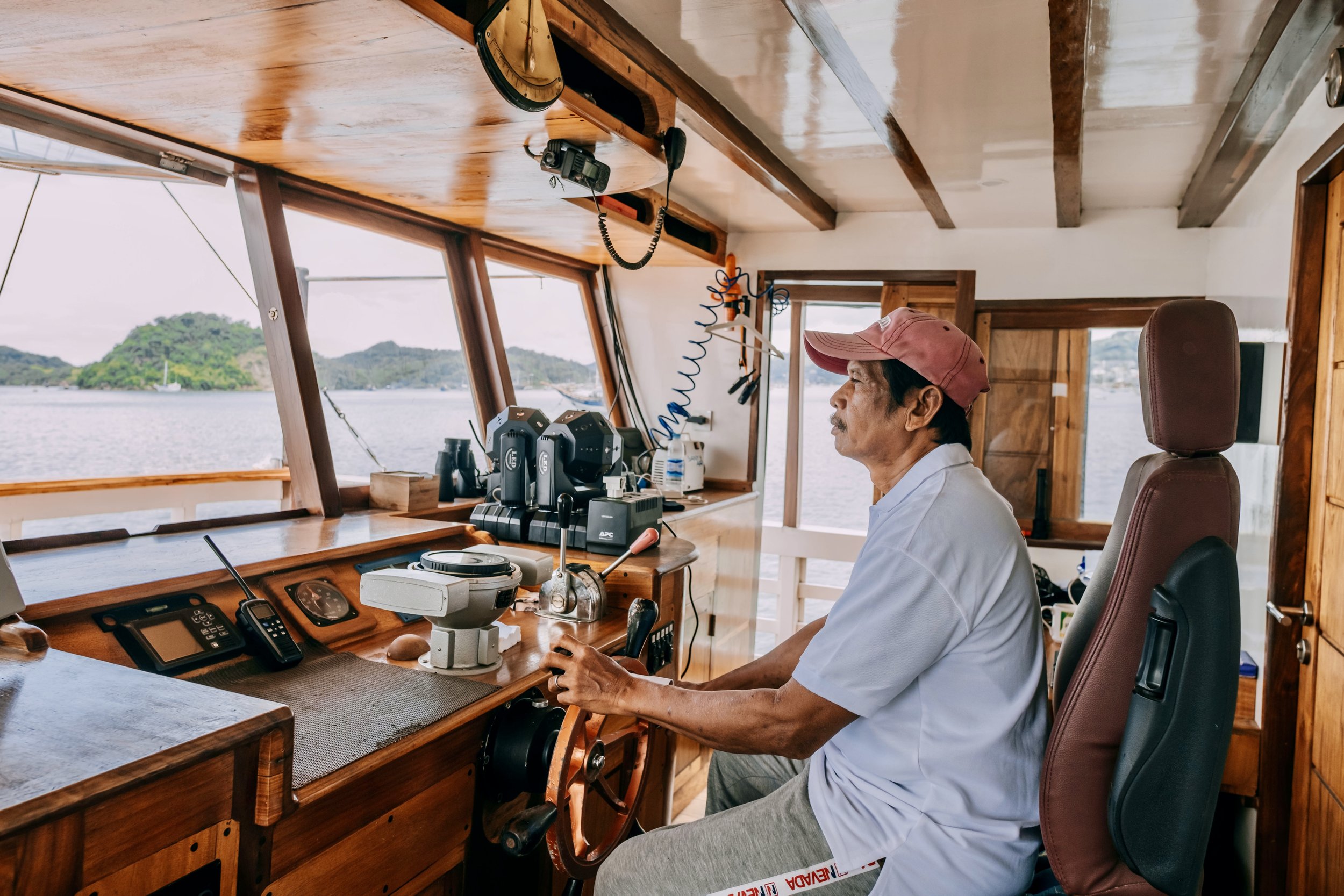 Phinisi boat captain guiding signature Komodo sailing journey during liveaboard expedition
