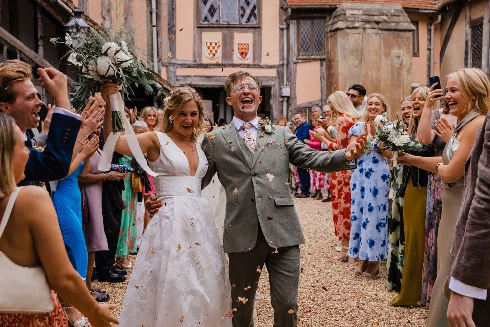 A bride and groom happy and smiling in a confetti throw at the Lord Leycester