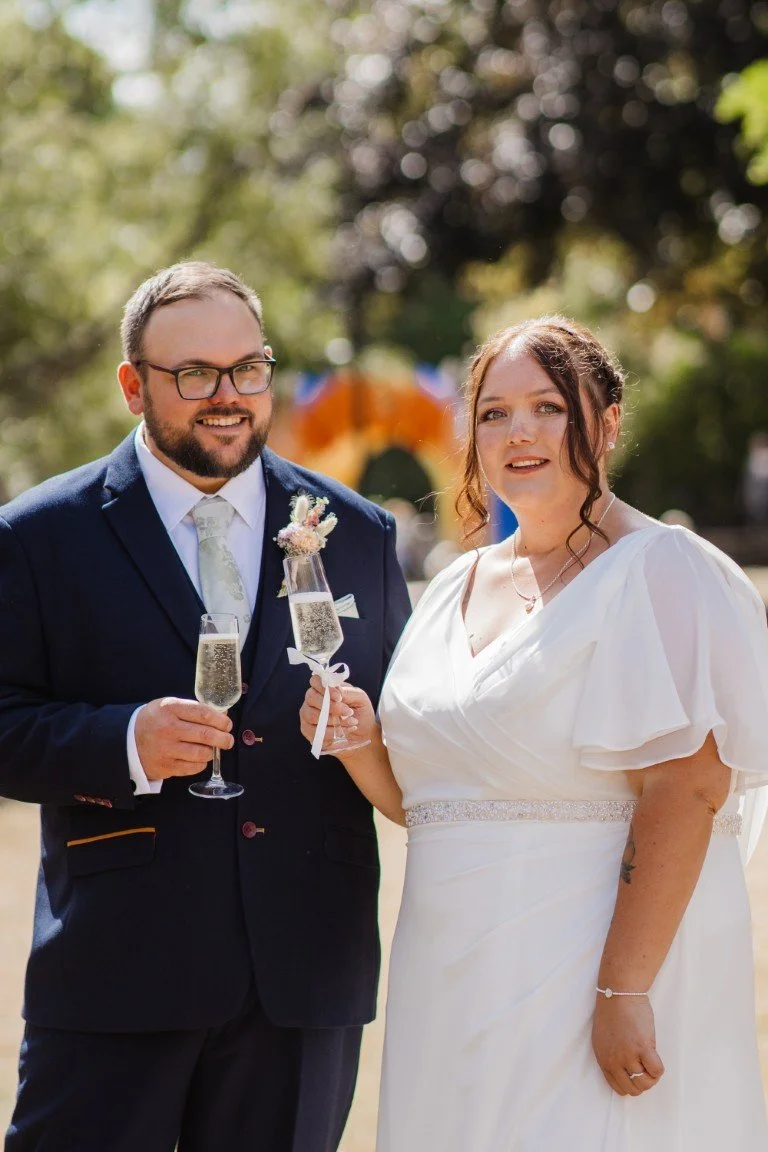 Bride and groom celebrating at their wedding outdoors with champagne glasses