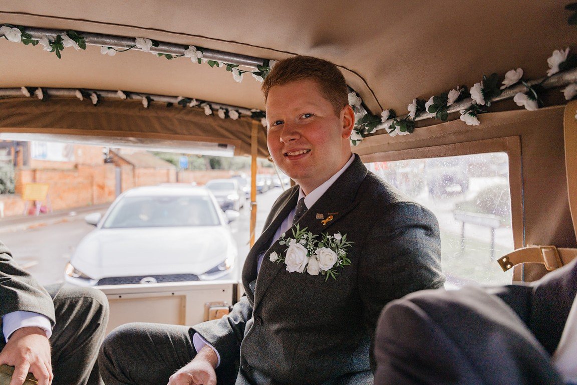 Man dressed in a suit with boutonnière inside a decorated vehicle