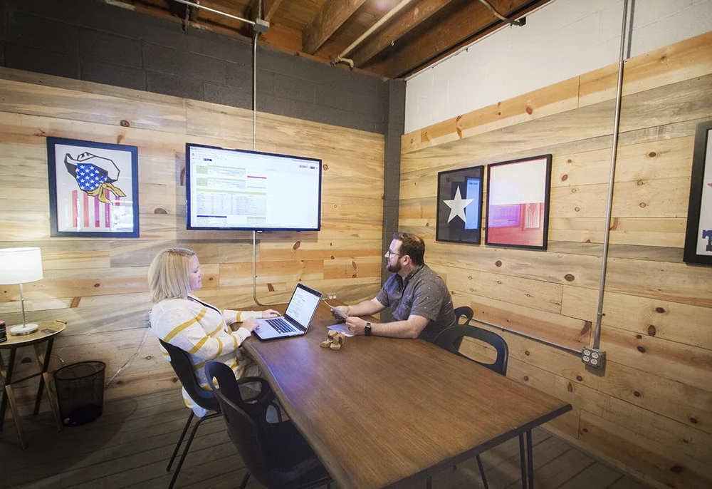 A wood-paneled conference room at Union Hall Workspace in Amarillo with a TV and seating for meetings