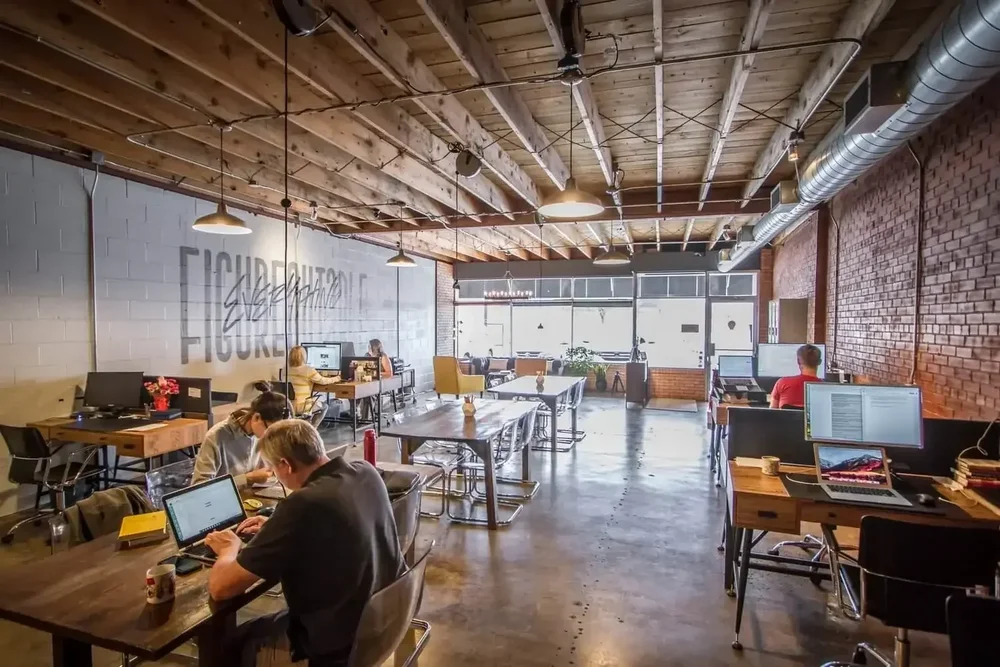Members working in the open coworking space at Union Hall Workspace Duniven, with brick walls and exposed beams