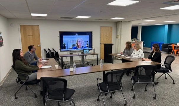 The Collective team meeting with five people in-person and one person meeting virtually.