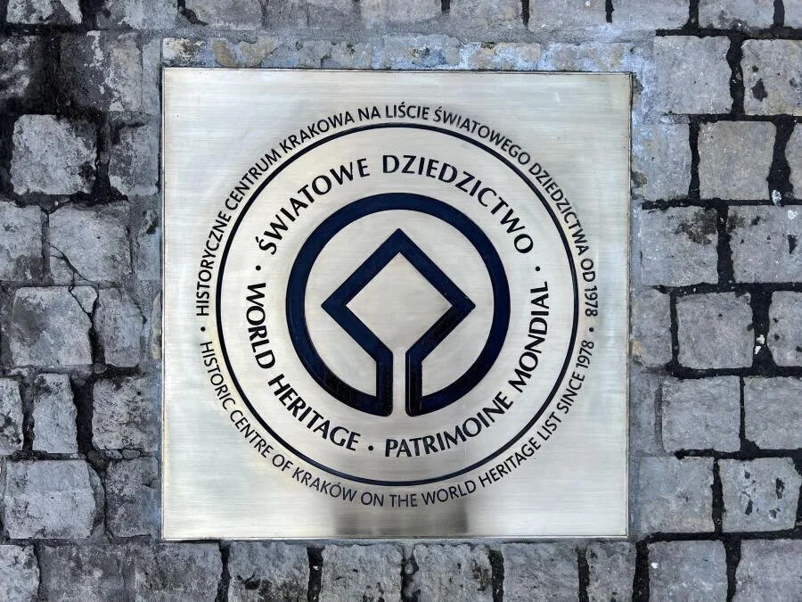 Plaque indicating World Heritage Site designation for the historic center of Krakow, Poland, on a brick wall.