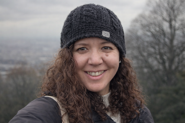 Three people taking a close-up selfie indoors, with a woman in the middle, a girl on the left wearing glasses, and a man on the right.
