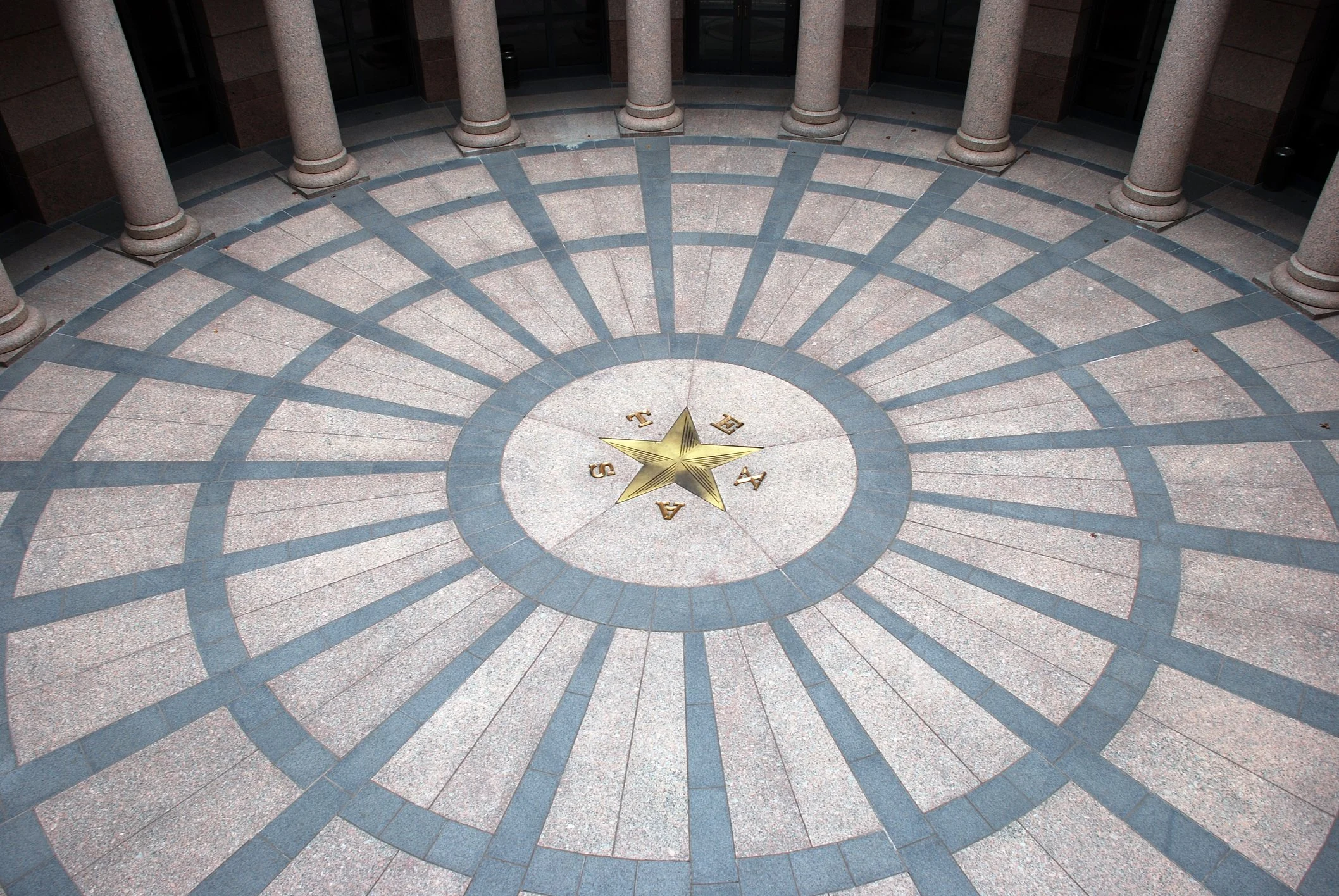 A circular granite floor with a star and the letters A, S, T, E arranged around it, surrounded by columns.
