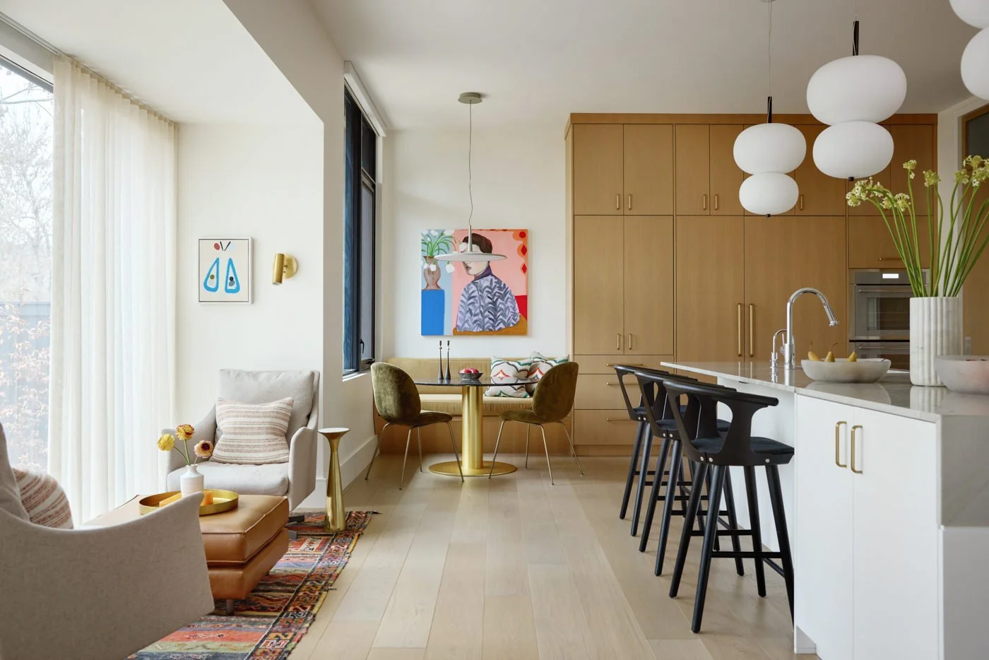 Open-concept living and kitchen area with modern decor, natural light, and wooden flooring.