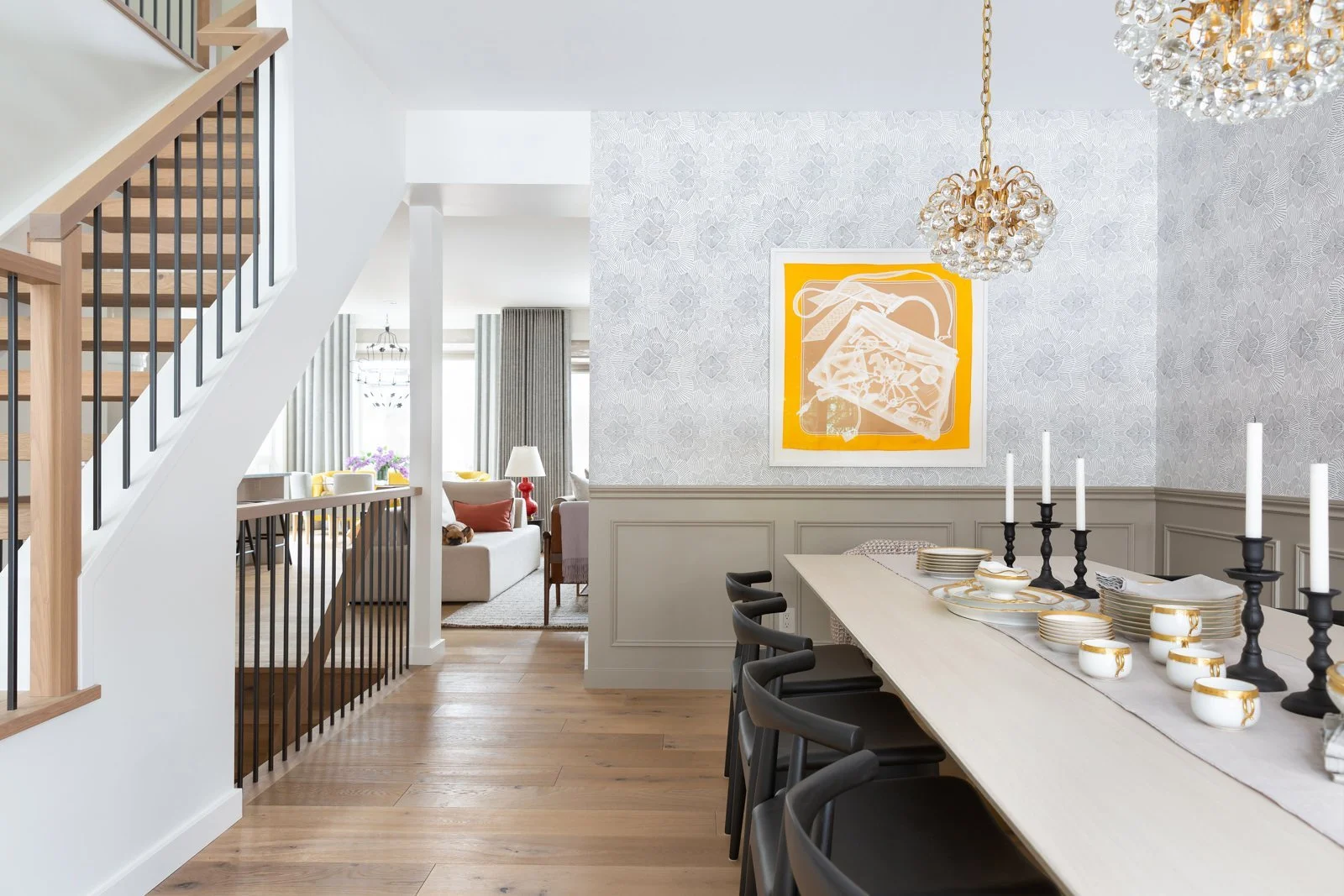 first wallpapered dining space with beautiful chandeliers and yellow modern artwork