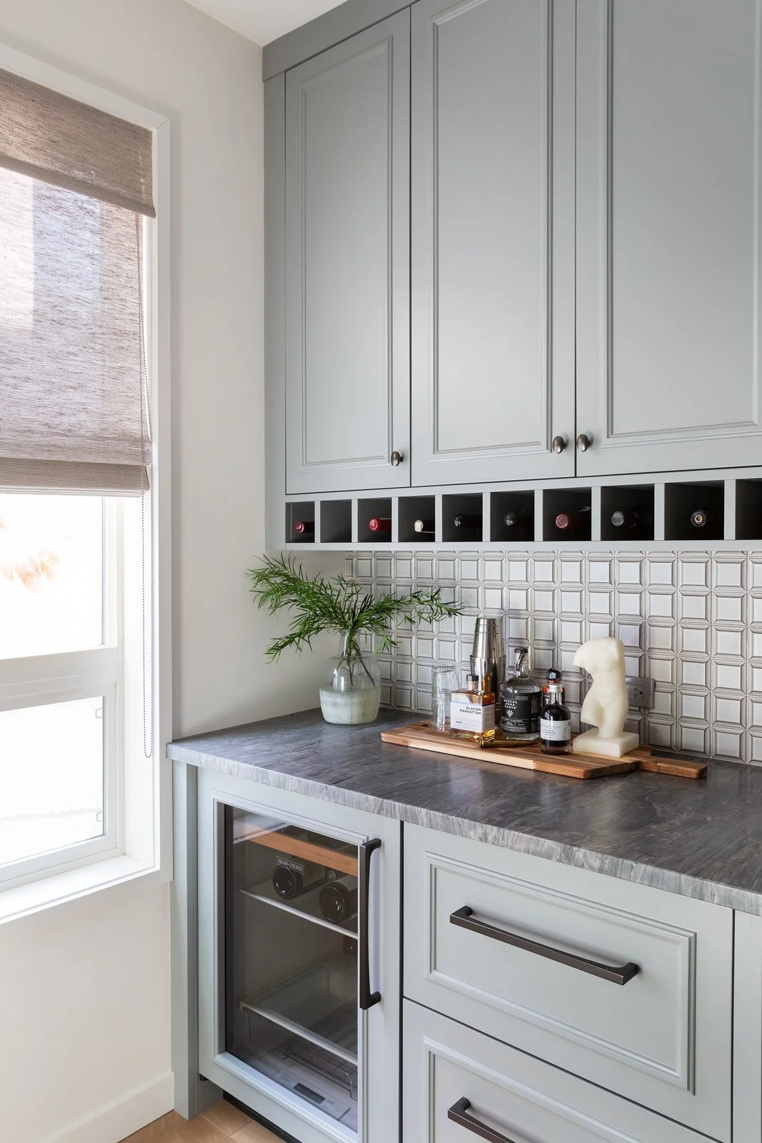pale blue cabinets in butler pantry with window and wine fridge