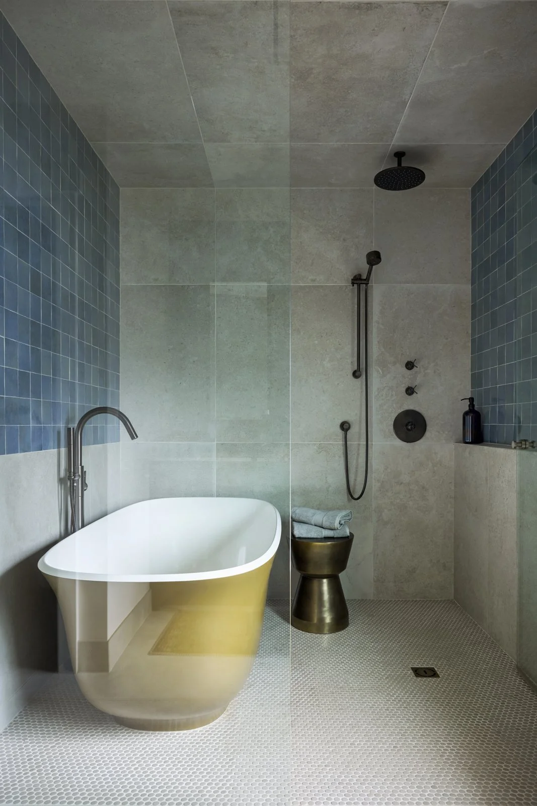 Modern bathroom with a yellow bathtub, blue tiled walls, and a walk-in shower with black fixtures.