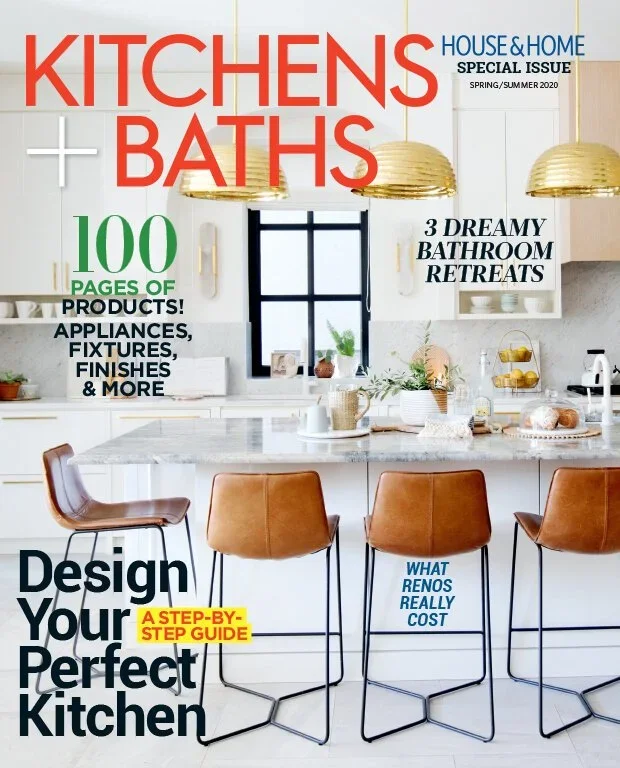 Cover of KITCHENS + BATHS magazine featuring a modern kitchen with a marble island, three brown bar stools, gold pendant lights, and a window with a black frame.