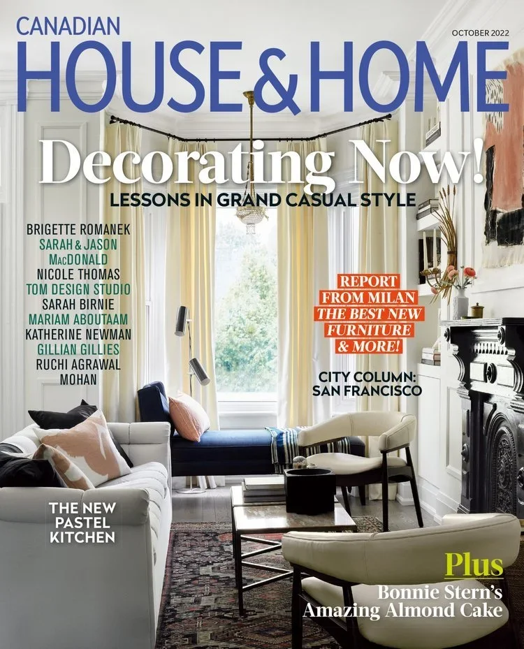 Cover of Canadian House & Home magazine, October 2022 issue, featuring a well-decorated living room with white and black furniture, a fireplace, large window with cream curtains, wall art, and decorative objects.