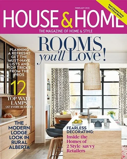 Cover of House & Home magazine, February 2019 issue, featuring a bright, modern kitchen with large windows, black and white patterned curtains, a wooden island, black chairs, and a hanging light fixture.