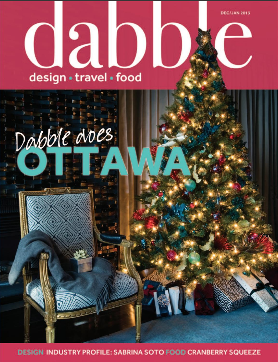 Cover of Dabble magazine with a decorated Christmas tree, wrapped presents underneath, a gold chair with a blanket and gift on it, and a Christmas tree topper with a dog-shaped figure.
