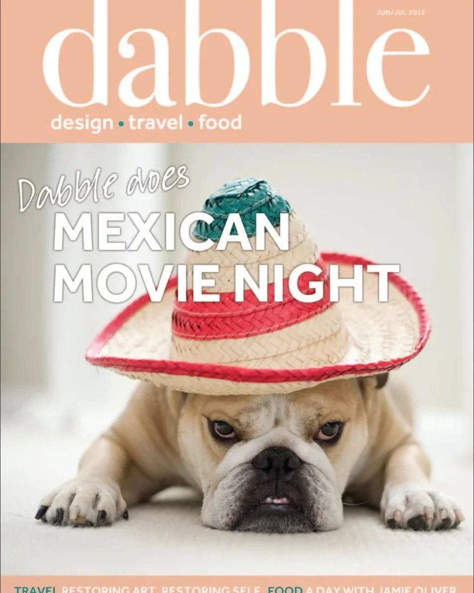 A dog wearing a colorful sombrero hat on a white surface.