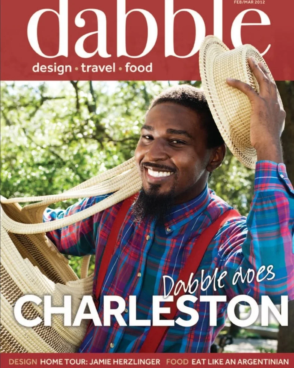 Magazine cover with a smiling man holding a straw hat and a woven bag, set against a green outdoor background. The magazine is titled "Dabble" and features topics like design, travel, and food. The headline reads "Dabble does Charleston."