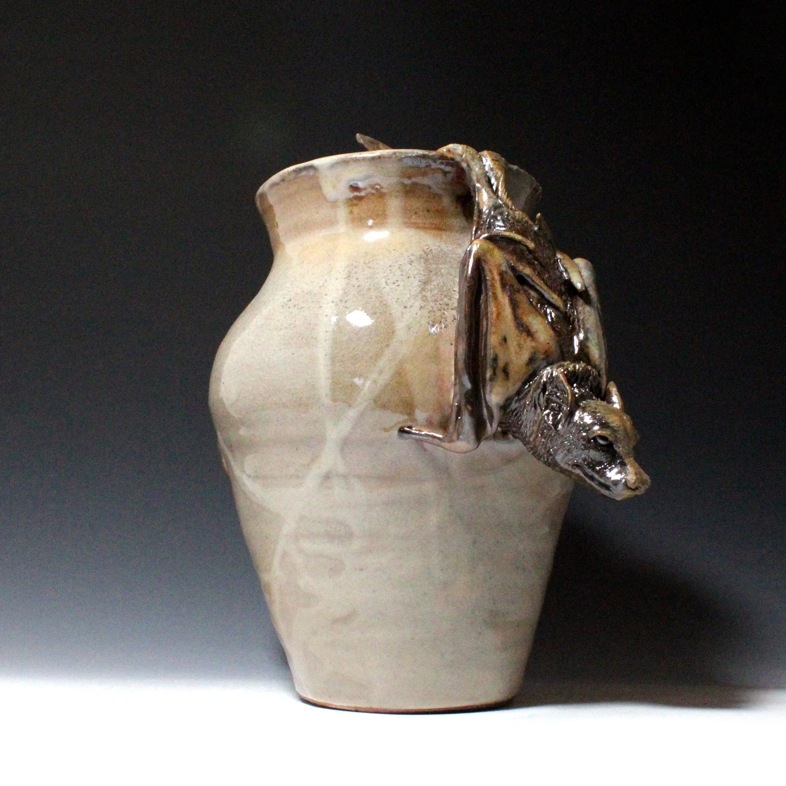 One Asian flying fox is awake, sniffing the air, wings tucked as it hangs from the rim of the vase.