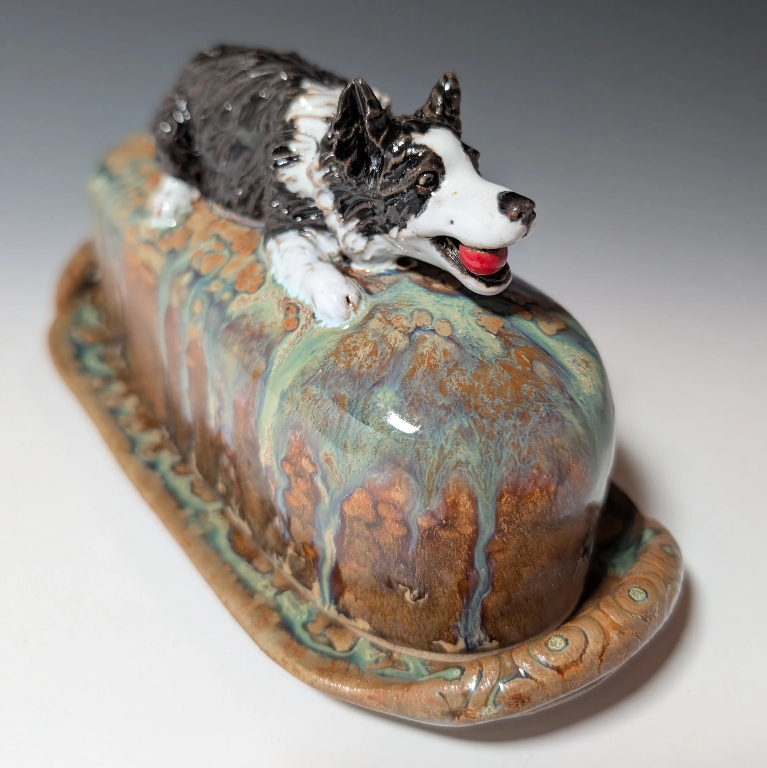 Handmade custom butter keeper with hand sculpted dog figurine in black and white on the top.