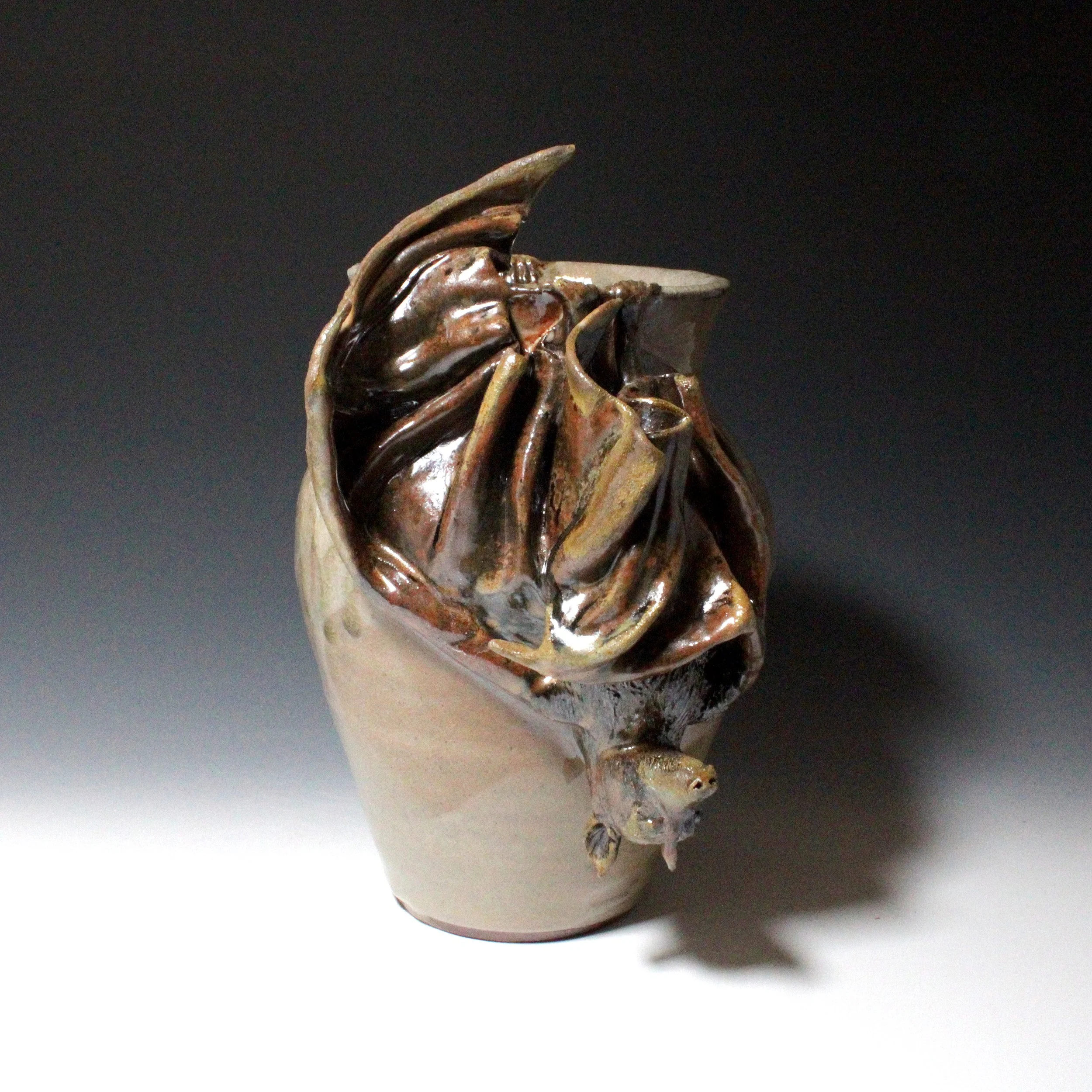 The second flying fox hangs mostly asleep, but with one wing unfolded as if waking.