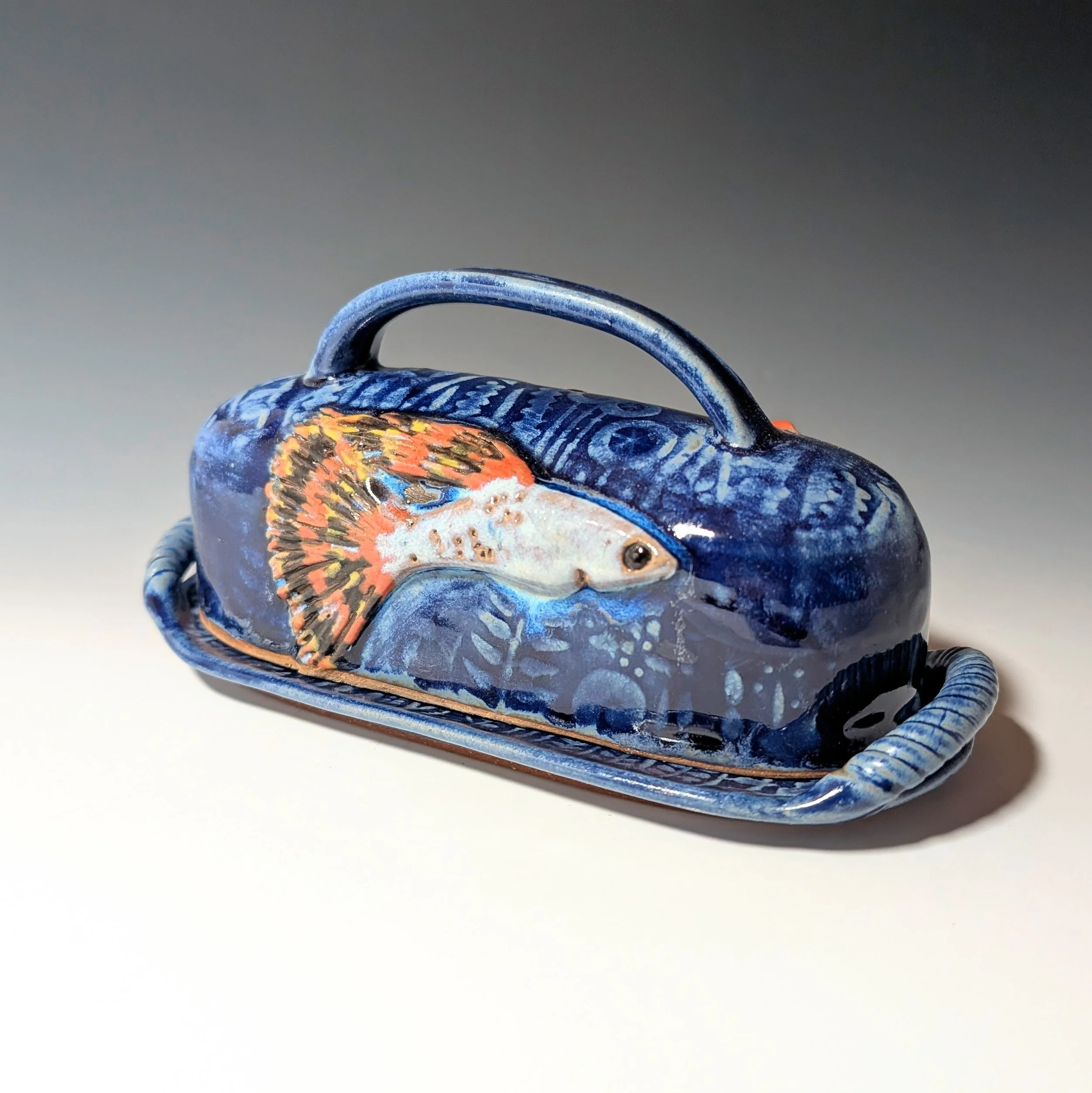 Handmade blue lidded butter plate with goldfish and fancy guppy original fish relief art.