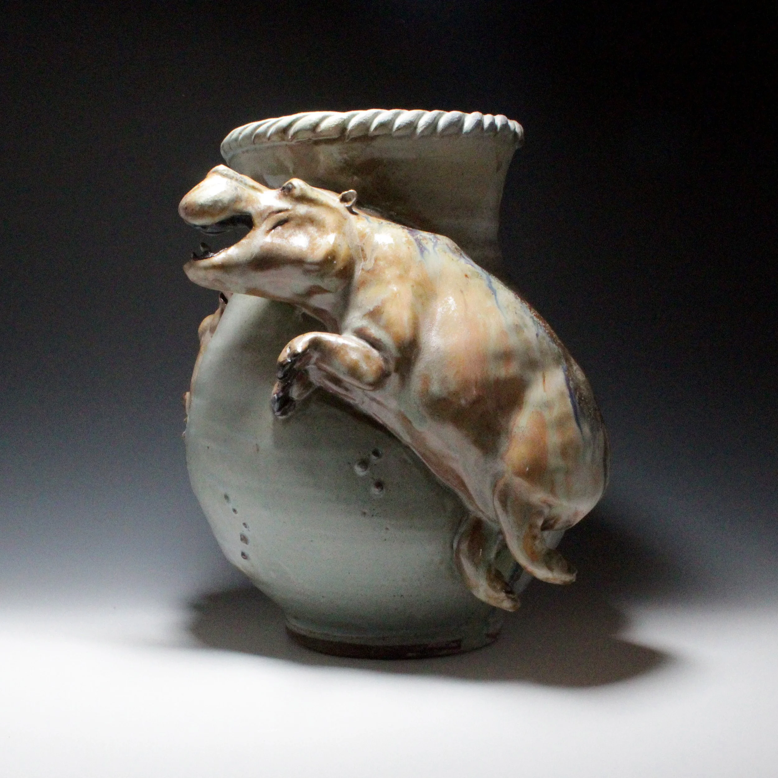So much movement and joy as a hippo mother plays with her babies on the sides of a smooth spiral rimed blue vase. 