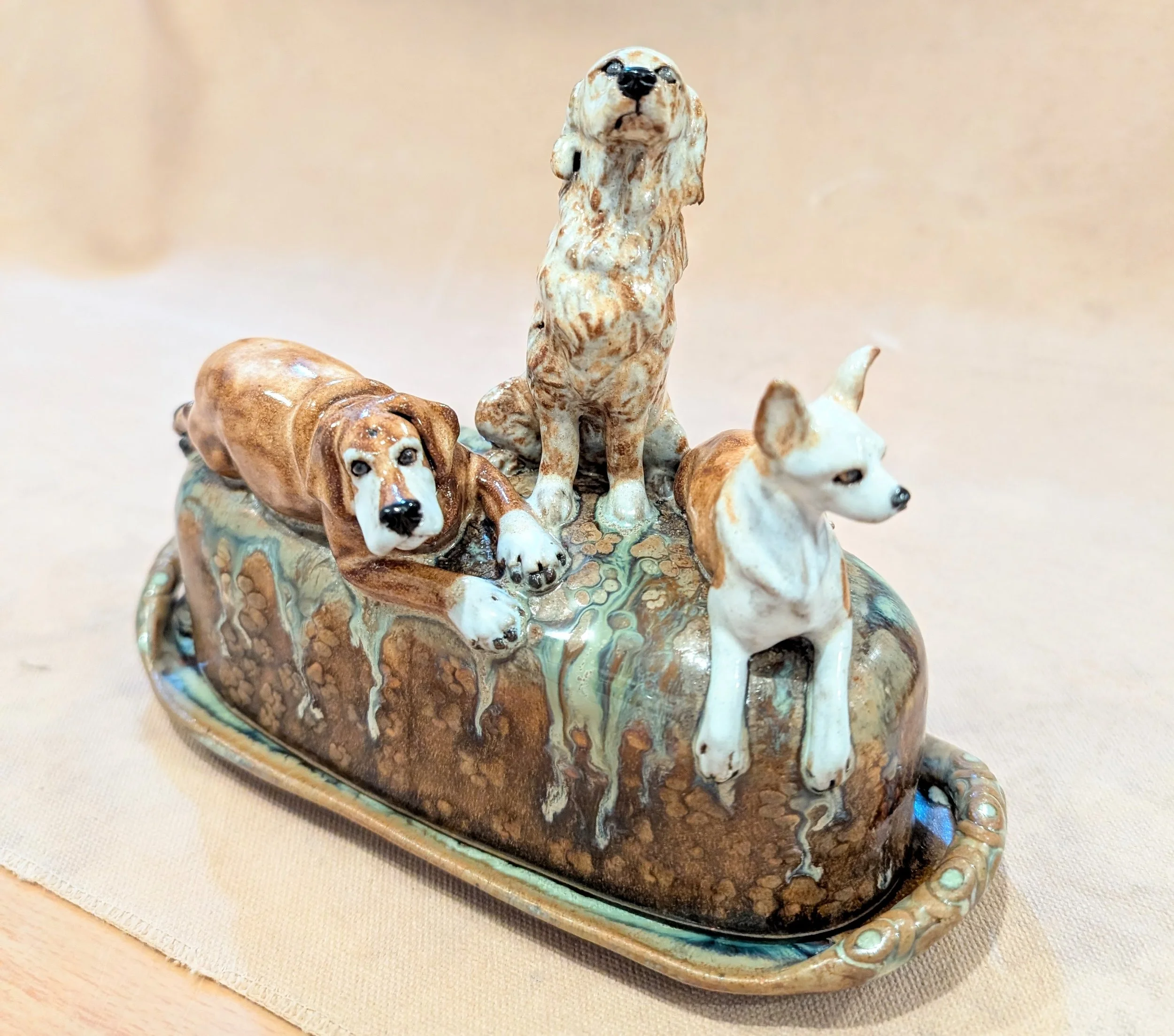 Custom made butter dish with three sculpted dog figurines on top.