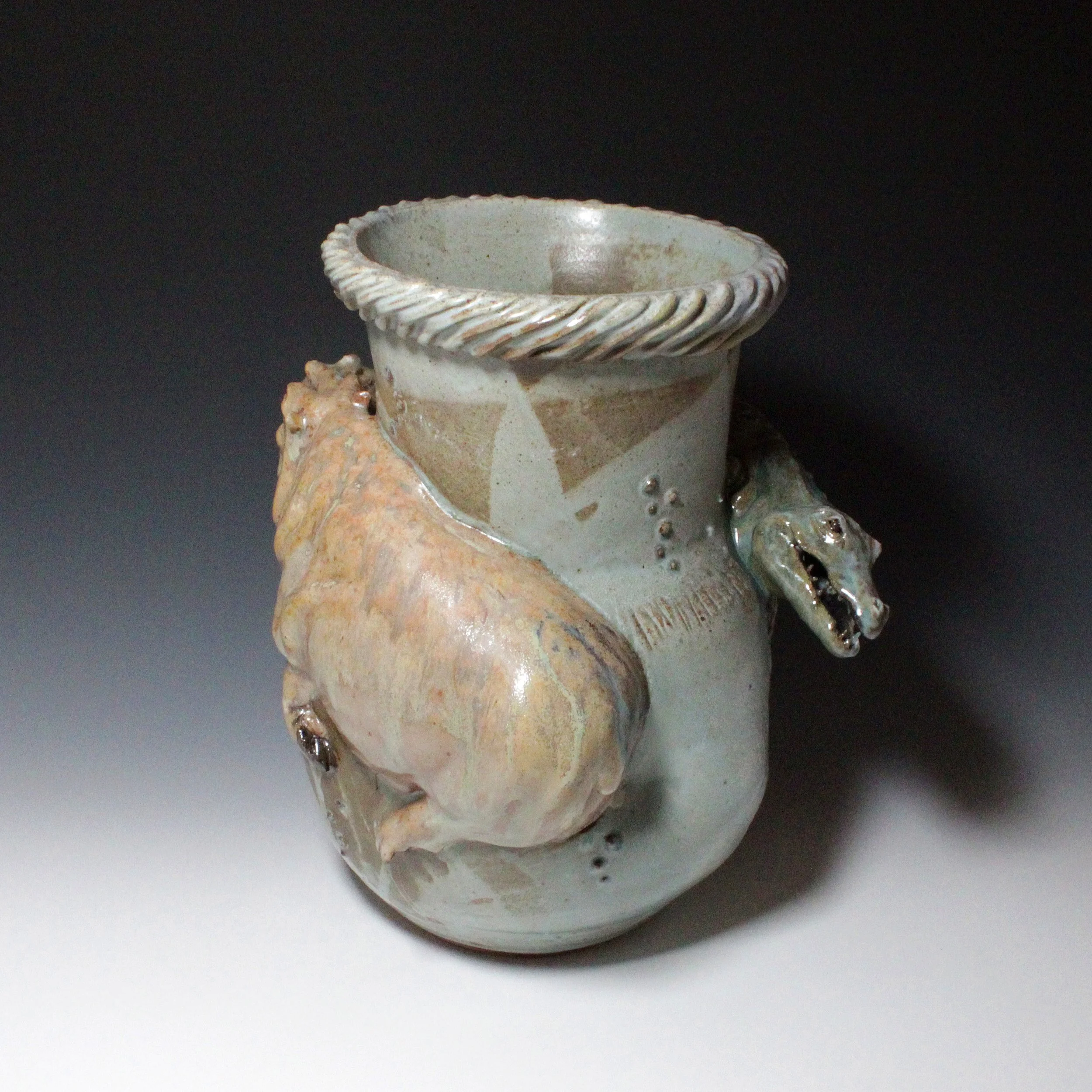 The glassy green alligator jaws that hang off the side of this large satin blue vase are dwarfed by the size of the satin brown rump of this attacking hippo. 